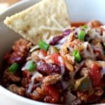 closeup of chili in bowl with a tortilla chip sticking out of chili.
