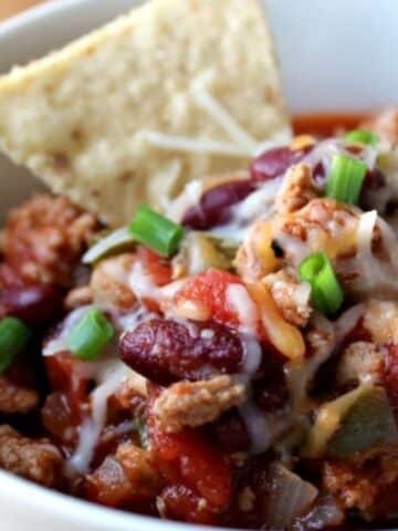 closeup of chili in bowl with a tortilla chip sticking out of chili.