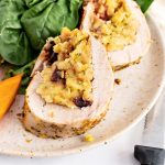 pork tenderloin stuffed , cooked and sliced on plate with spinach and vegetables