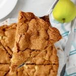 slice of apple cake held above the rest of the cake on a serving spoon