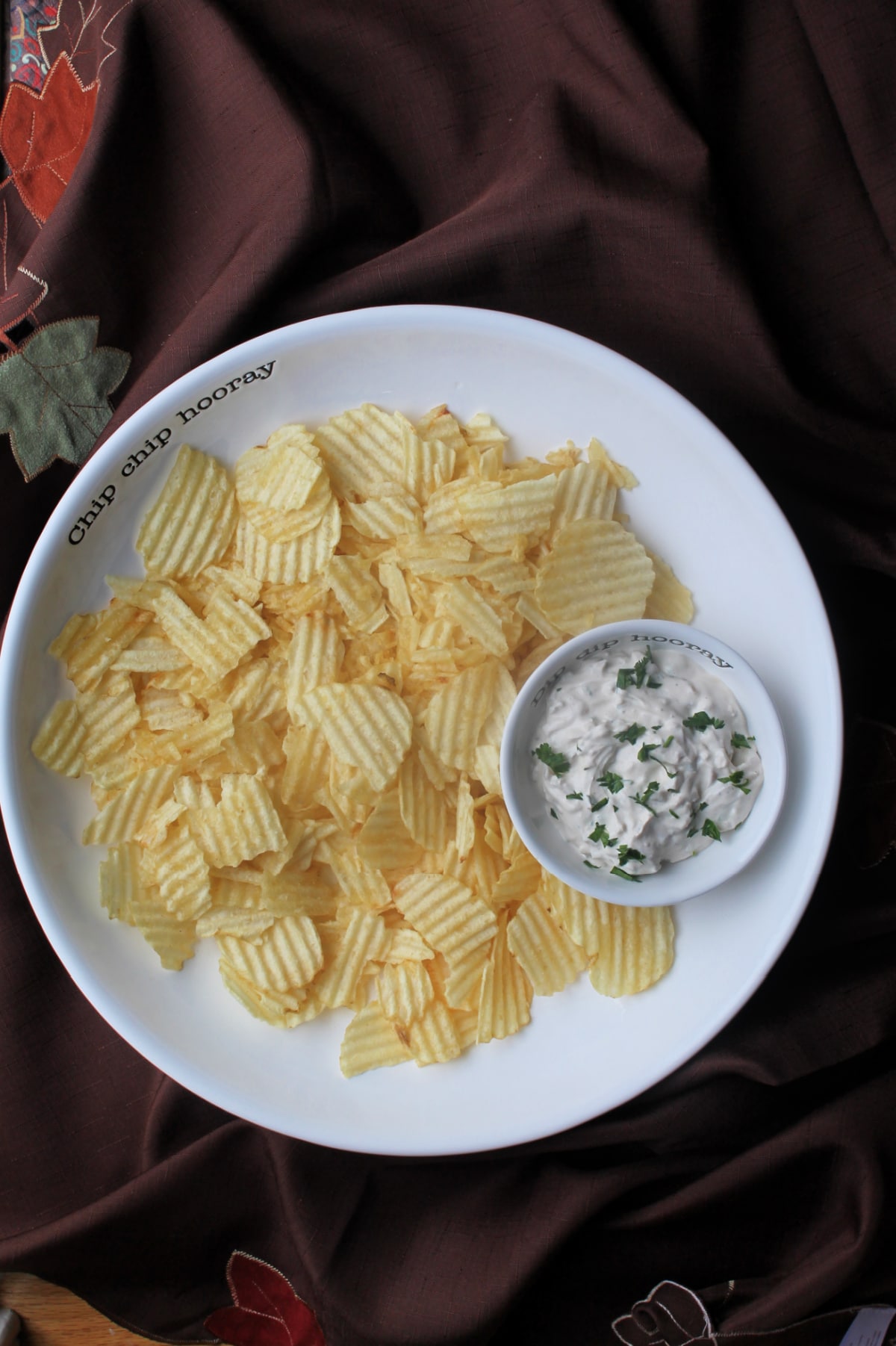 onion dip in serving bowl with potato chips surrounding it