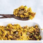 stuffing on wooden spoon over baking dish