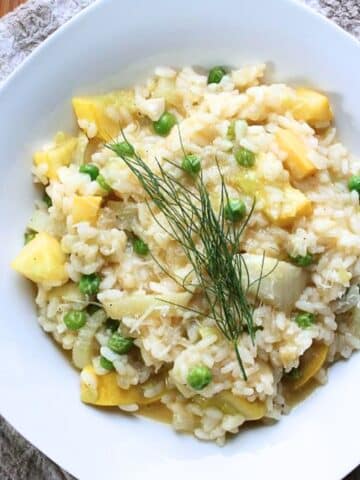 Aerial view of prepared vegetable risotto in a white square dish.