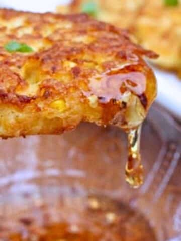 A prepared corn fritter that is dripping with honey.