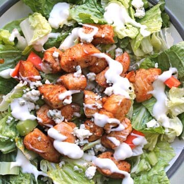 close up view of salad topped with buffalo chicken and dressing.