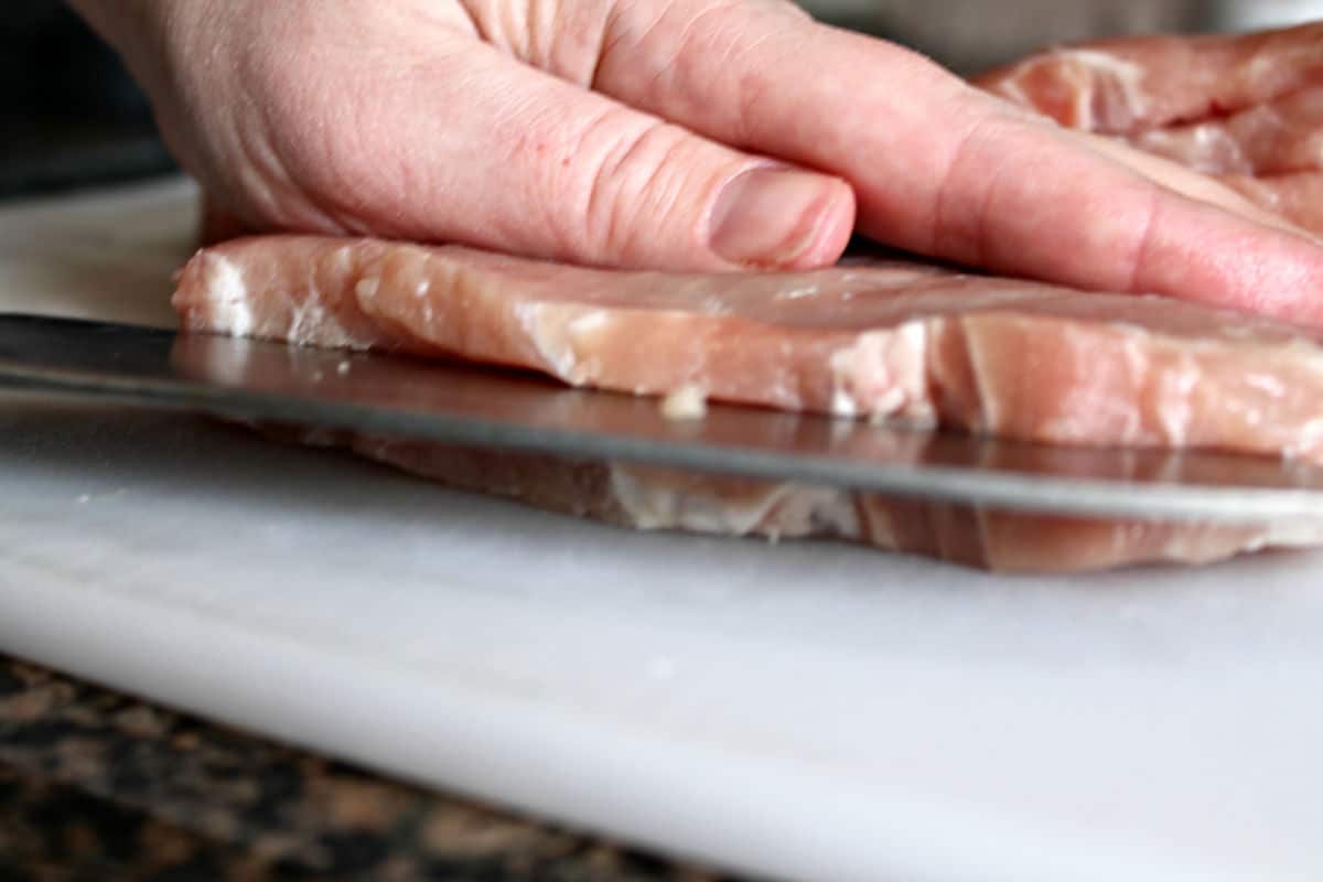 pork chop being sliced to create a pocket for stuffing