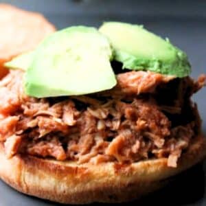 pulled chicken on the bottom of a roll, topped with avocado slices.