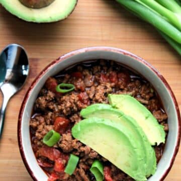 bowl of prepared chili topped with sliced avocado.