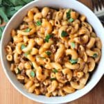 Close up overhead view of prepared cheeseburger macaroni in a white bowl.