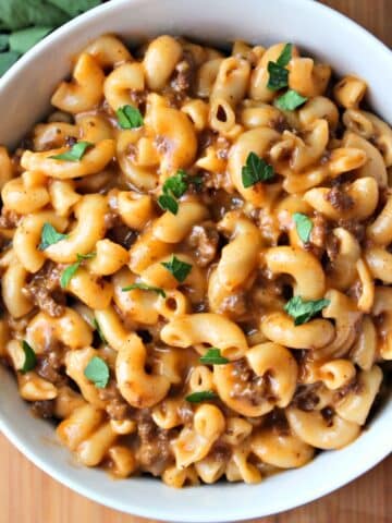 Close up overhead view of prepared cheeseburger macaroni in a white bowl.
