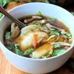 potsticker soup in white bowl with spoon in bowl