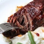 close up of fork breaking up country style beef rib on plate