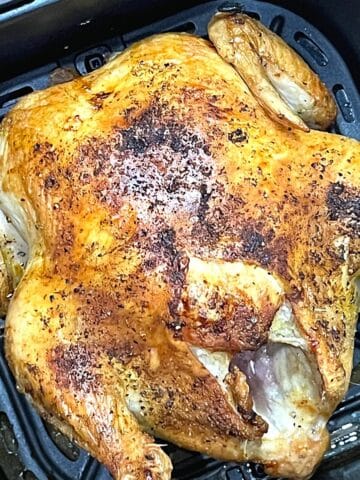 whole chicken in the air fryer basket, cooked.