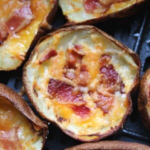 Close up of crispy, cooked potato skin with bacon and cheese. The potato skin is still in the air fryer basekt.