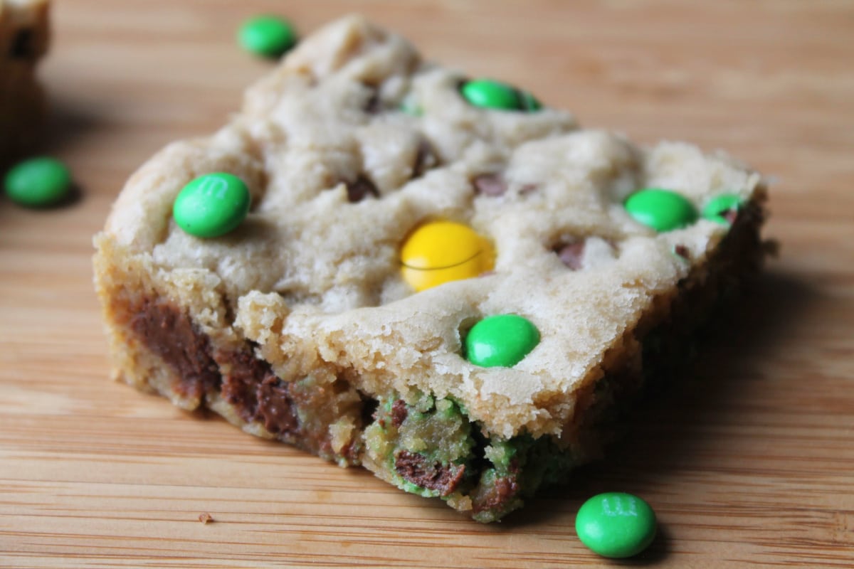 1 cookie bar with green and yellow m&m candies on a cutting board, close up