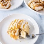 iced caramel apple danish on white plate with fork cutting a bite off