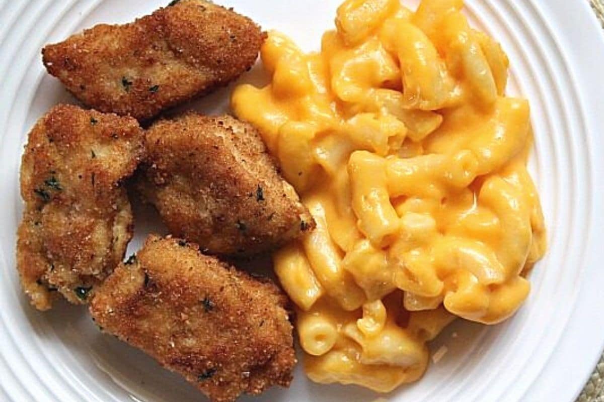 Chicken nuggets and mac and cheese on a white place.