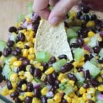 hand dipping a tortilla chip into the tomatillo salsa