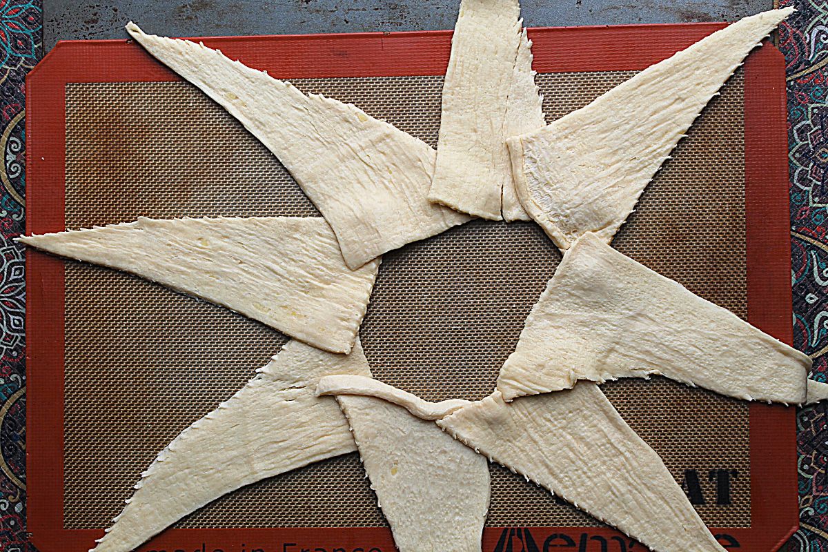 crescent dough on lined pan in the shape of a star.