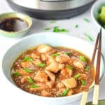 Close up view of cooked chicken teriyaki in a white bowl. There are chopsticks balanced on the right side of the bowl.