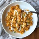buffalo chicken rice bowl in a white bowl. the bowl is on top of a striped towel.