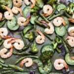 Cooked shrimp and veggies on a sheet pan.