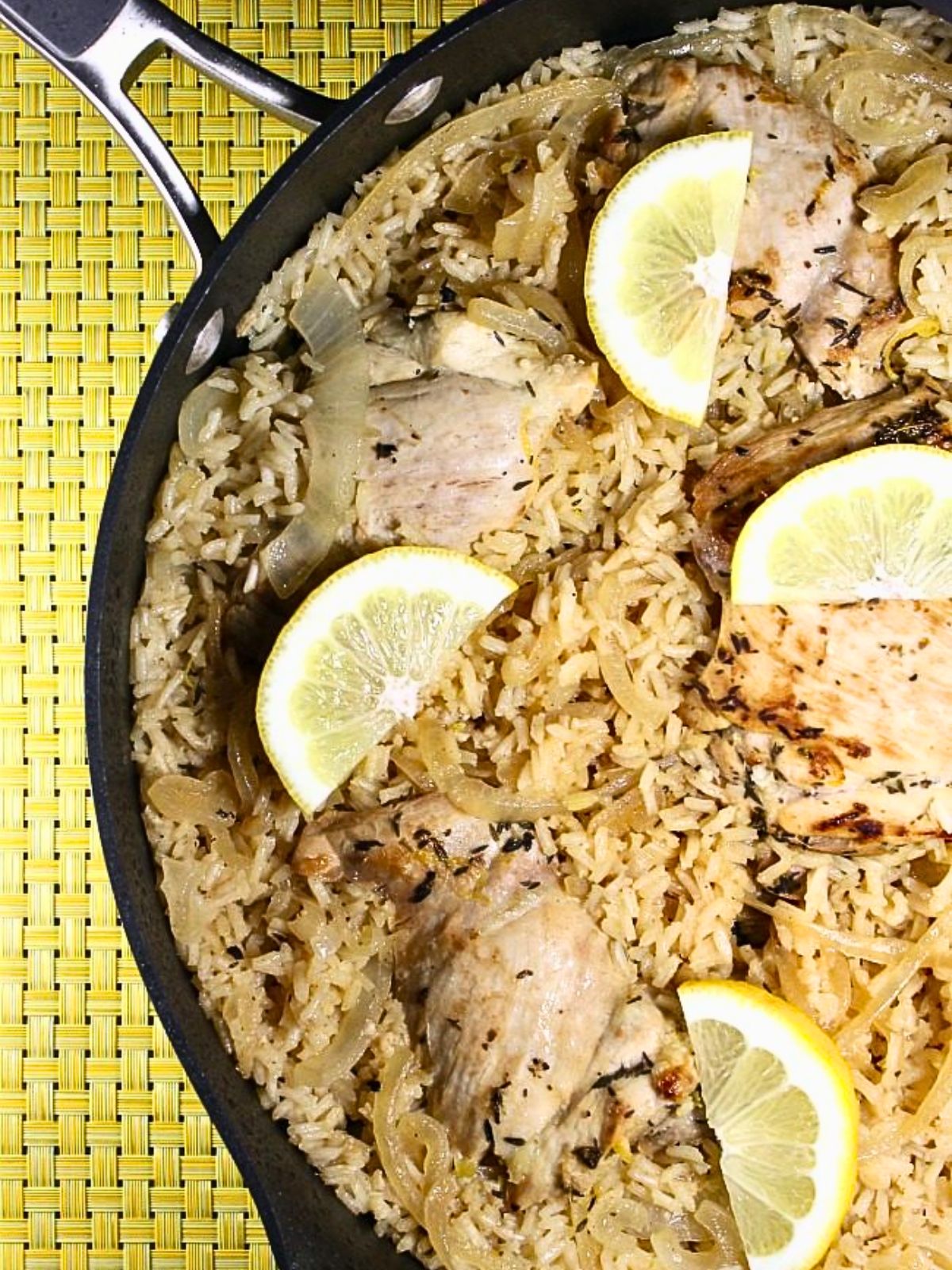 Overhead view of half of the skillet. In the skillet is the prepared recipe with lemons on top.