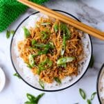 Aerial view of prepared chicken on top of rice in a bowl.