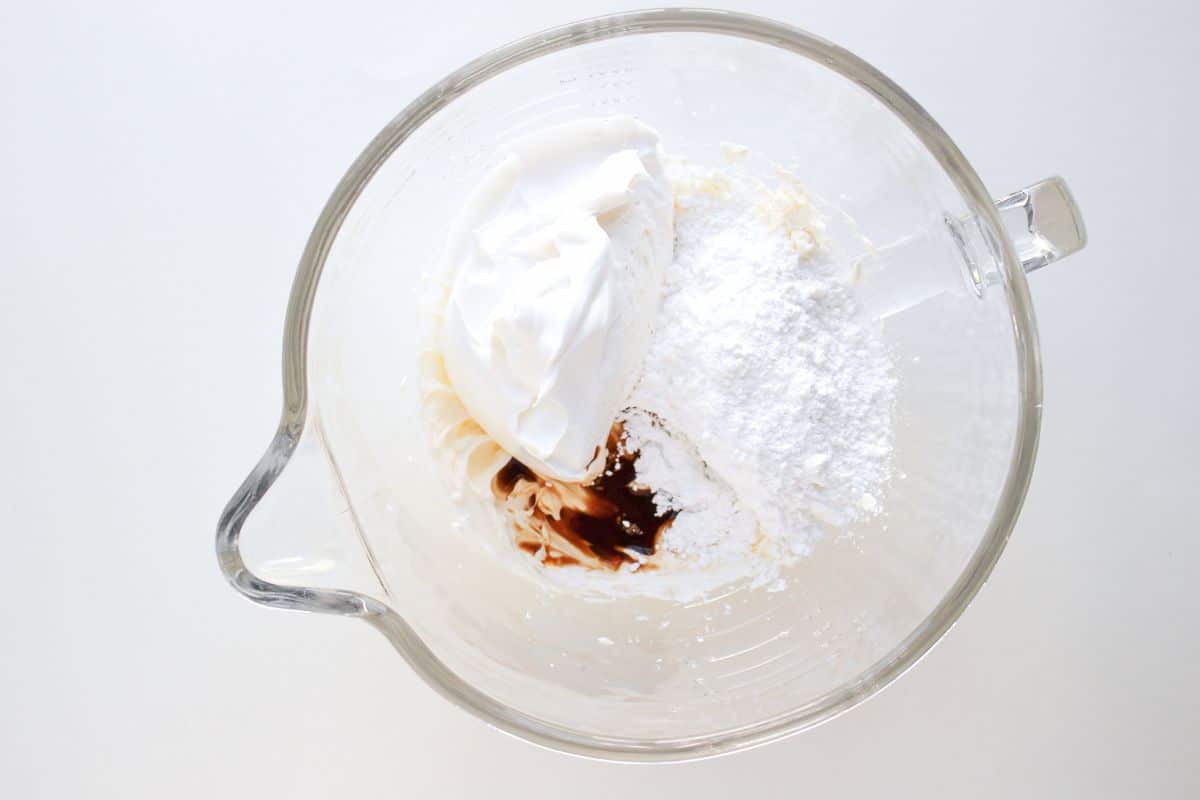 A glass bowl with the ingredients to make the cream cheese base of the dip.