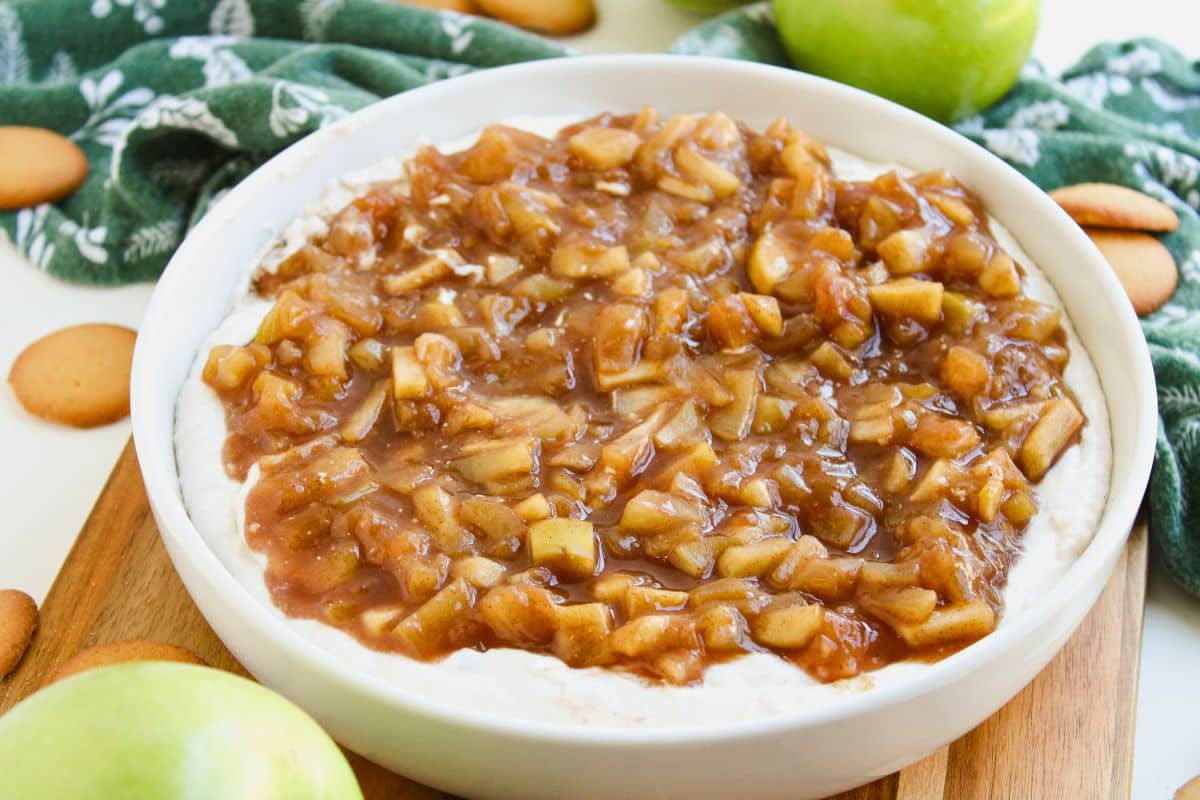 The prepared dip in a shallow white bowl sitting on a wooden slat.