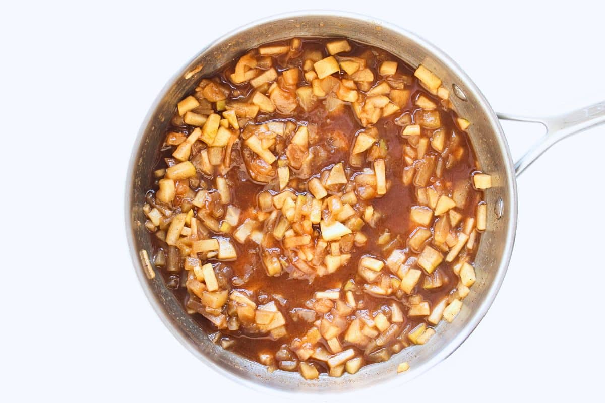 Cooked apple pie filling in stainless steel pan.